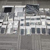34 téléphones, tablettes et autres appareils de communication électronique saisis par la GRC et rangés dans des sacs de preuves après la perquisition du domicile utilisé par Mansouri et Alouah.