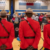 Trois agents en tunique rouge et des élèves d'une école secondaire admirent la Coupe Grey