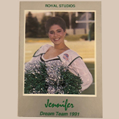 Une meneuse de claque avec des pompons vert et blanc prend la pose et sourit pour la photo.