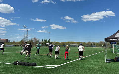 Several people run away from the camera and down a soccer field.
