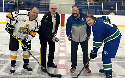 Hockey players from opposing teams smile for the camera ahead of puck drop.