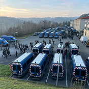 Un groupe de policiers se dirige vers un stationnement de véhicules de police.