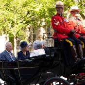 Deux gendarmes dirigent la calèche ouverte où se trouvent le Roi Charles, la Reine Camilla et deux autres personnes.