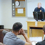 Un homme en vêtements civils parle à un groupe de nouveaux cadets en vêtements civils.
