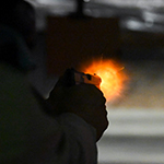 Un cadet tire avec son pistolet sur une cible dans un champ de tir obscur.