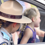 Une cadette portant un chapeau Stetson montre à une fillette comment utiliser les feux d'urgence d'une autopatrouille.