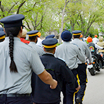 Un groupe de cadets marche derrière une file de motocyclettes pendant un défilé.