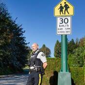 RCMP officer conduct speed enforcement in a school zone with 30 km/hr speed sign in the top right corner
