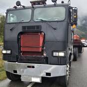 An Alberta-based tractor-trailer with no front grill, a cracked windshield, missing windshield wipers, and other defects being pulled over by BC Highway Patrol