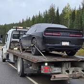 A black Dodge Challenger on the back of a tow truck on Highway #1 near Golden, BC