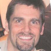 43-year-old man, with brown hair, blue eyes and a goatee.