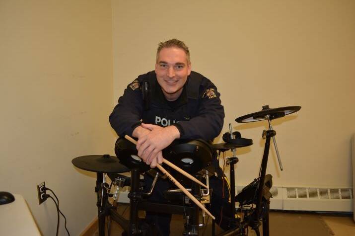 A male <abbr>RCMP</abbr> officer sits behind an electric drum set
