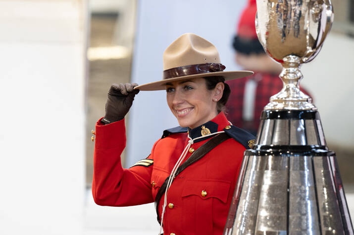 An officer in Red Serge is seen posing with the Grey Cup
