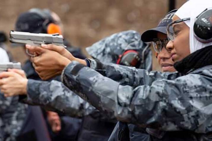 Woman points gun during firearms training at a shooting range.