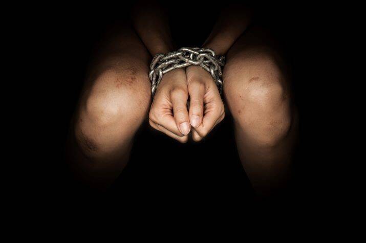 Close-up of a pair of hands bound with chains.