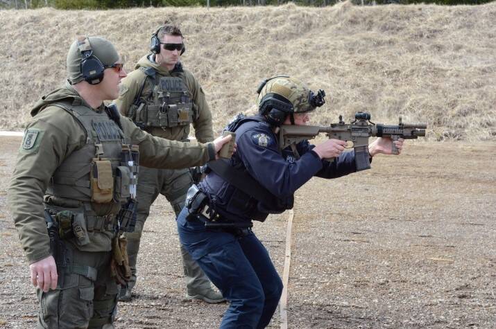 Female police officer shooting a long gun.