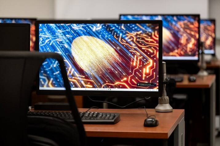 A computer lab setting with multiple monitors displaying a digital fingerprint as the desktop background