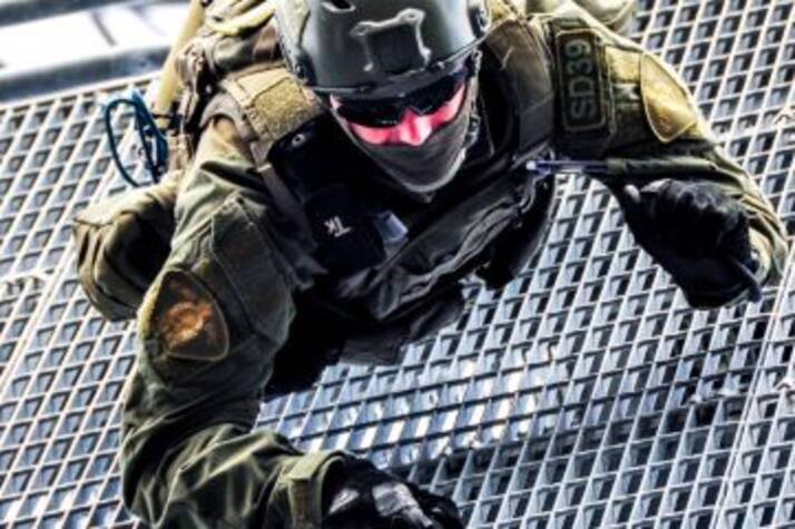 An RCMP Emergency Response Team member climbs down a metal grate during a training exercise.