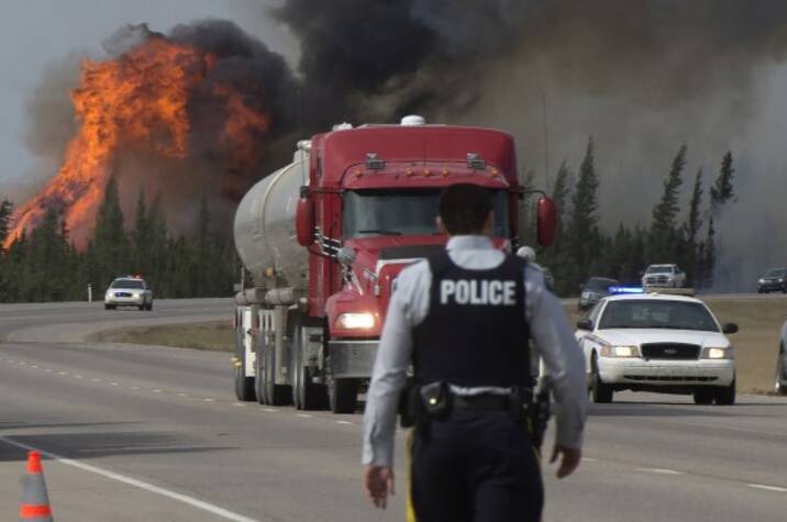 RCMP officer walks on road near forest fire.
