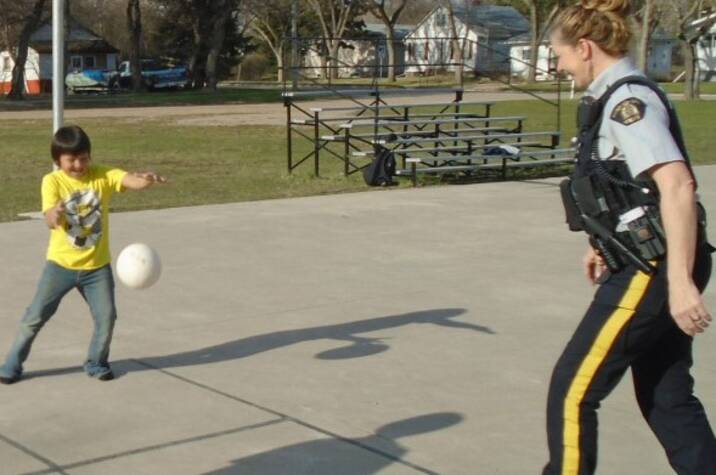 Police officer playing ball with children.