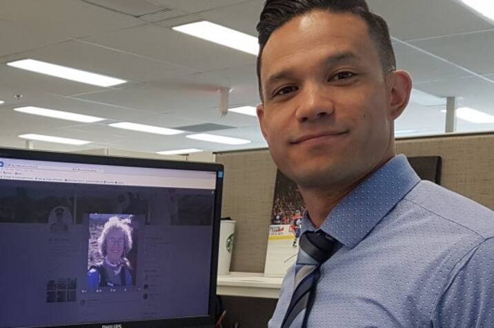 Police officer standing in front of computer screen.