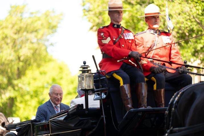 Black open carriage drawn by two horses and coachmen in Red Serge.