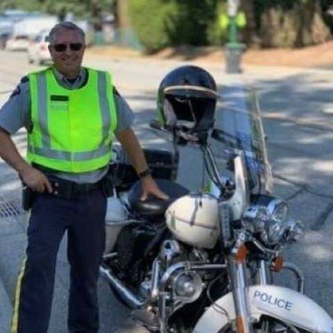 RCMP Traffic Service Supervisor conduct speed enforcement with a white RCMP motorcycle to his right