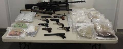 Photo of Firearms, cash, and illicit drugs seized during search warrants at Surrey and Richmond properties on a table.