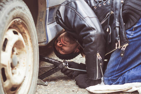 Homme regardant sous une voiture